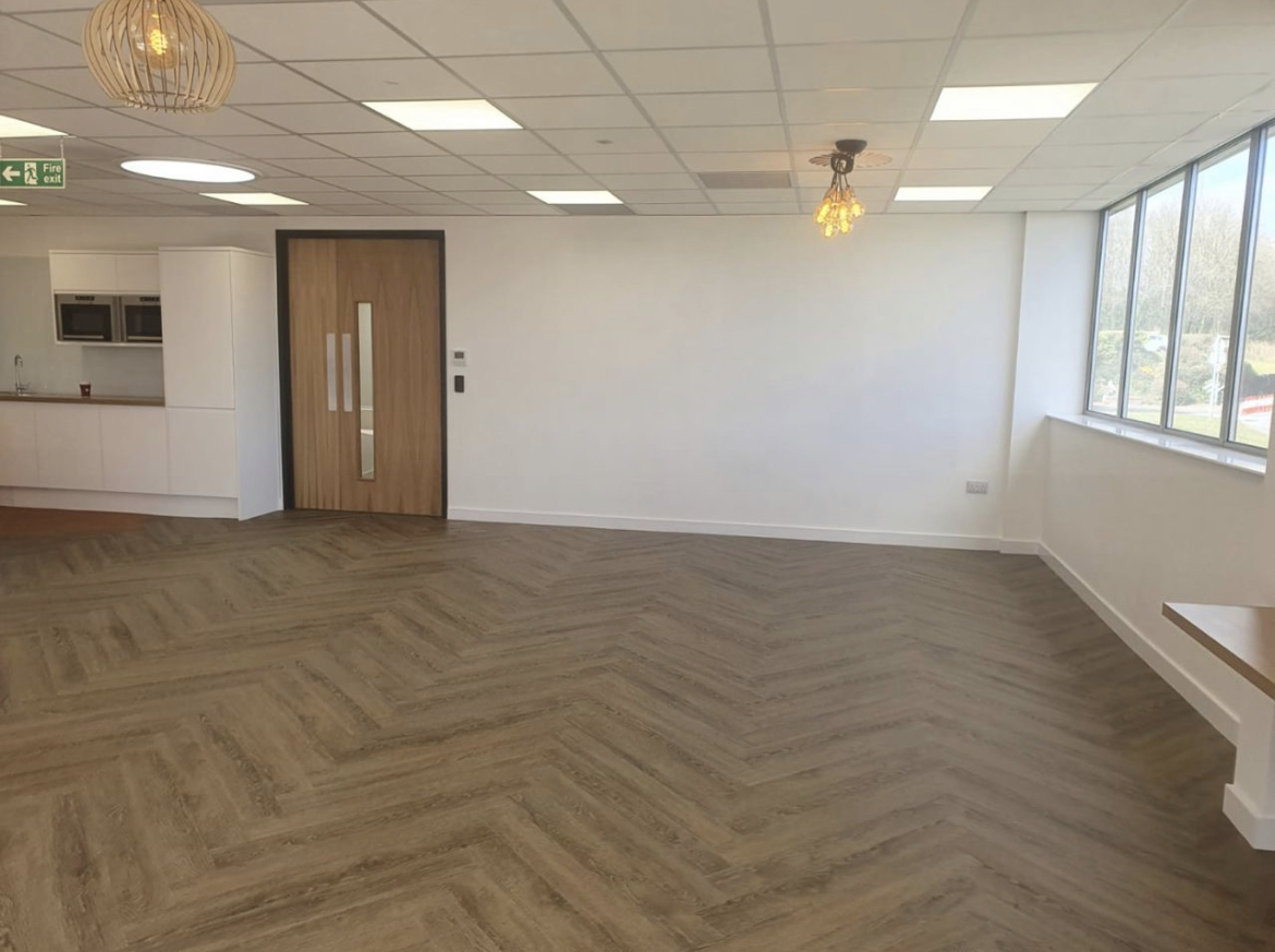 Photograph of recently redecorated modern office space with white walls and parquet flooring.