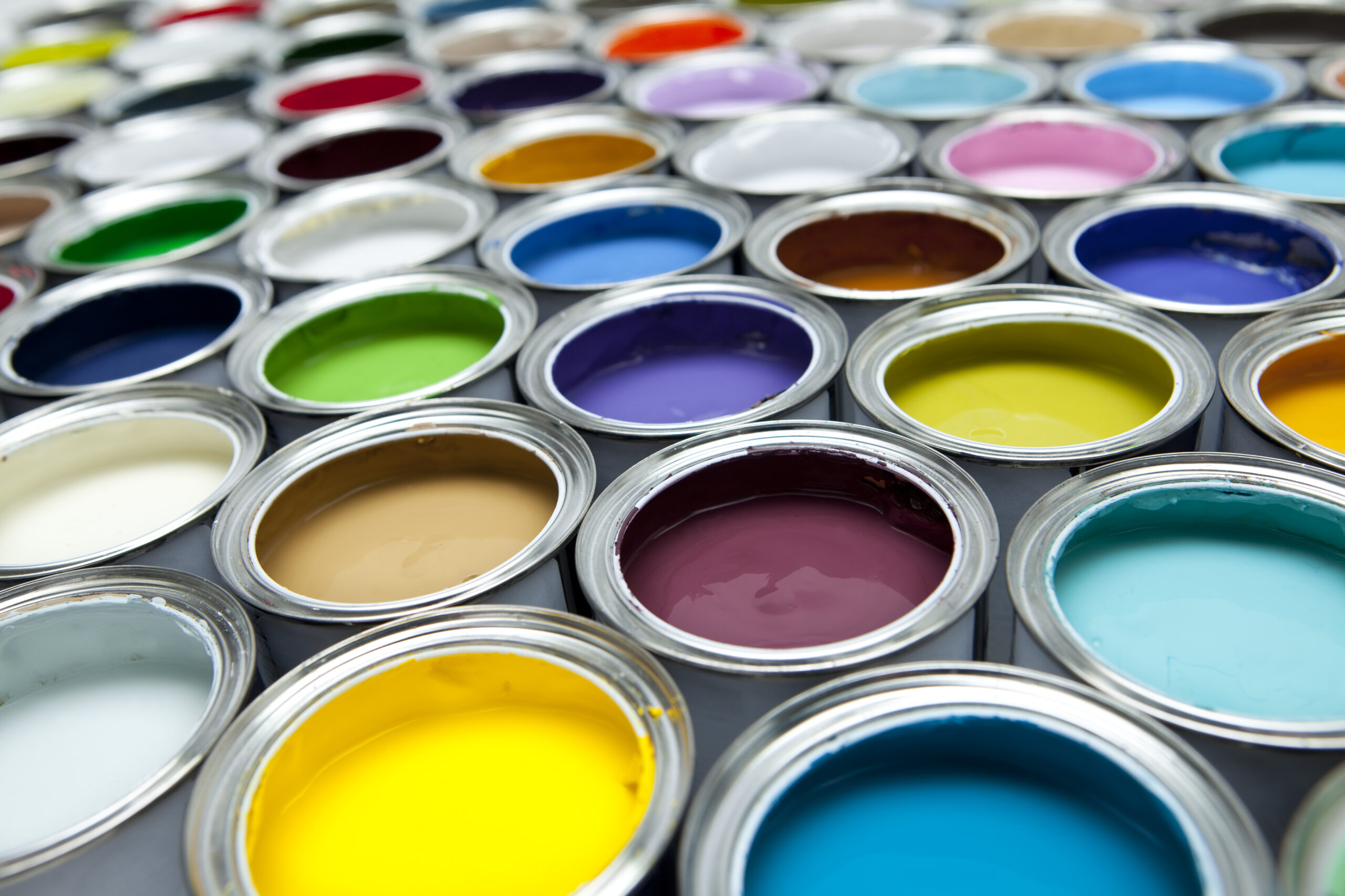 A colourful selection of open commercial paint pots in a variety of colours.