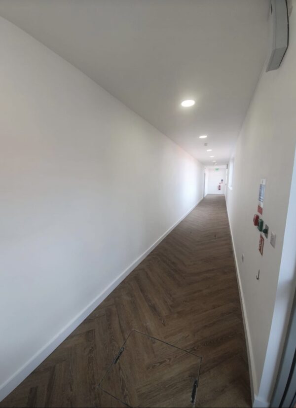 Corridor with white walls and parquet wooden flooring.