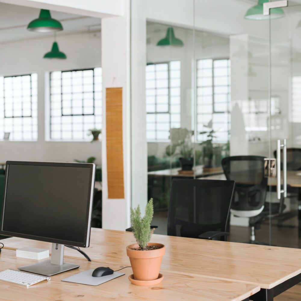 Modern office with white walls and black chairs with accent green lamp shades on ceiling.