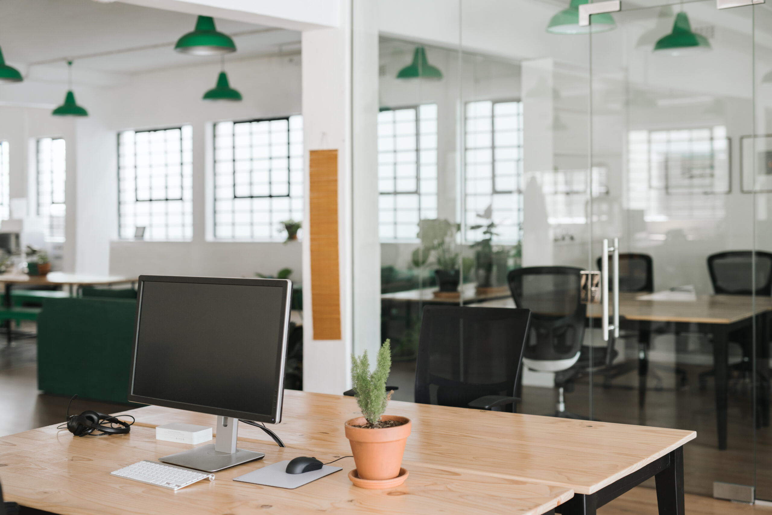 Modern office with white walls and black chairs with accent green lamp shades on ceiling.