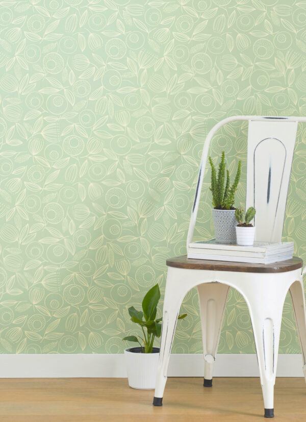 White chair with houseplants on seat, with green botanical wall covering in background.